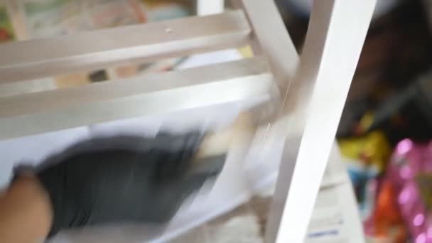 Someones hand is painting the wooden elements of furniture with white paint. — Stock Video