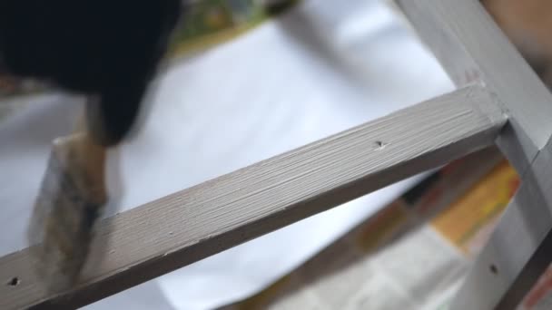 Qualcuno sta dipingendo con pennello parte in legno di mobili in colore bianco. Fatto a mano — Video Stock