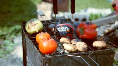 Erkekler mangalda sebze çeviriyor.