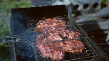 Aşçı ateşte etle ızgarayı çevirir. Piknik konsepti.