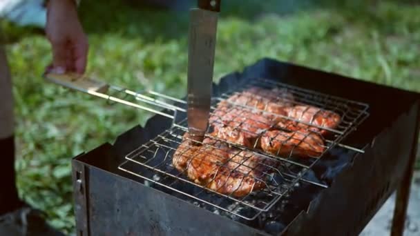 A szakács egy késsel ellenőrzi a hús készségét a grillen. a piknik fogalma. — Stock videók