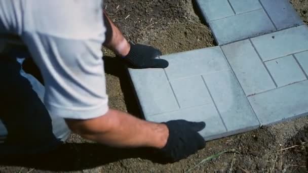 Homem coloca uma telha de pavimentação cinza. — Vídeo de Stock
