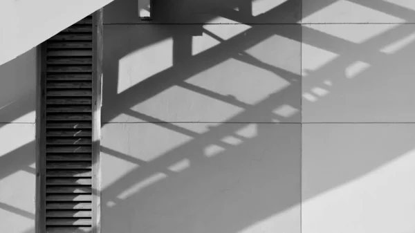 shadow of fire exit staircase on white cement wall - abstract background