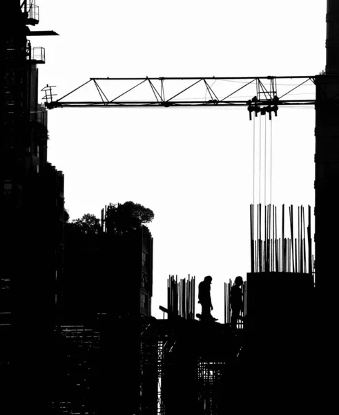 Silhouette of engineer standing orders for construction crews to work safely on high ground over blurred building background