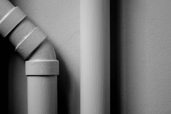 white plastic pipe at white cement wall with shadow.