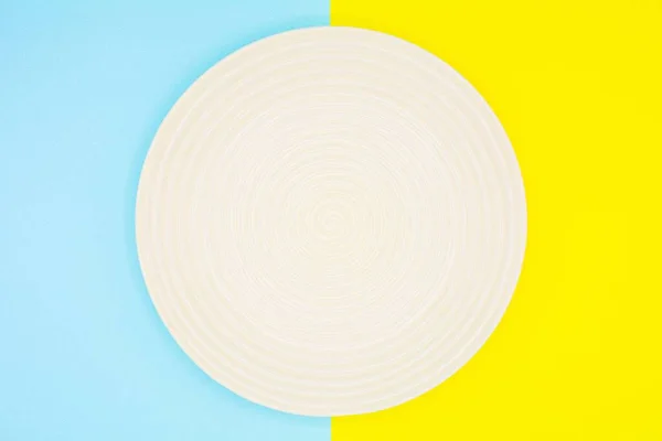 青と黄色の紙の上の白いセラミック料理 — ストック写真