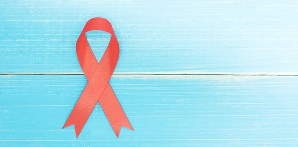 蓝木背景上的红色缎带上的艾滋病意识标志 — 图库照片