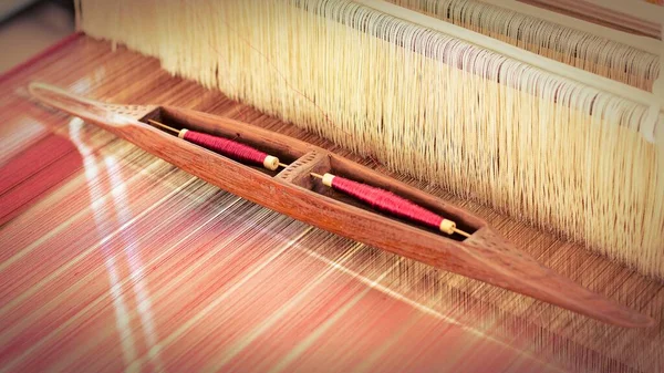 antique wooden bobbin on silk thread. - traditional weaving of silk.