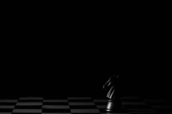 黑暗背景下棋盘上的黑马象棋 商界领袖概念 — 图库照片