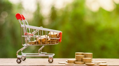 Alışveriş arabasında altın paralar ve ahşap masada altın paralar. - Reklam ve fotokopi alanı için..