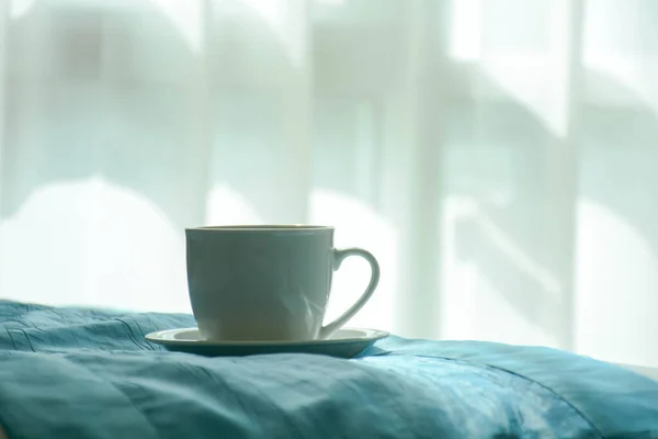 朝ベッドの上の白いコーヒーカップ — ストック写真