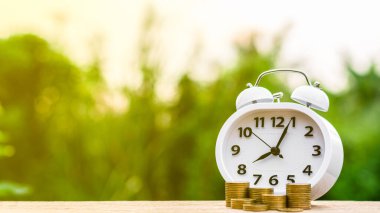 Retro çalar saat ve masanın üzerinde bir yığın altın para. - Fırsat kavramı zaman ve para tasarrufu gerektirir..