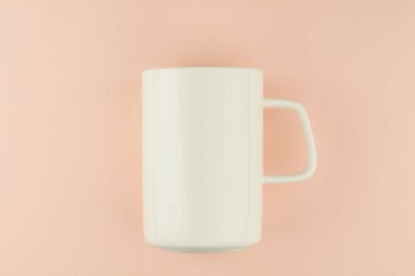 Pembe arka planda beyaz seramik kahve fincanı.