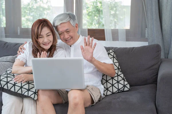 Happy Asian Senior Couple  lifestyle technology device concept,Lovely elderly couple using laptop computer vdo call with Their family