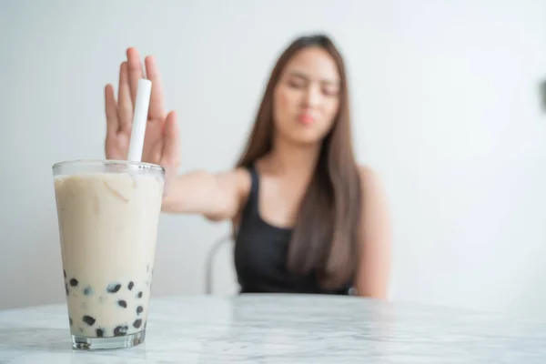 Close up Asian Diet Women using hand push out her favourite Bubble milk tea and choose green apple and vegetables for good health. dieting and health care concept.