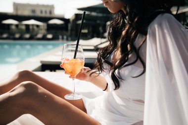 Genç kız havuz kenarında soğuk bir kokteyl içiyor.