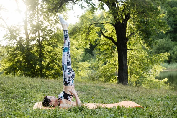 The girl is engaged in fitness and meditates in the park city — Stock Photo, Image