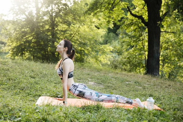 Девушка занимается фитнесом и медитирует в парке города — стоковое фото