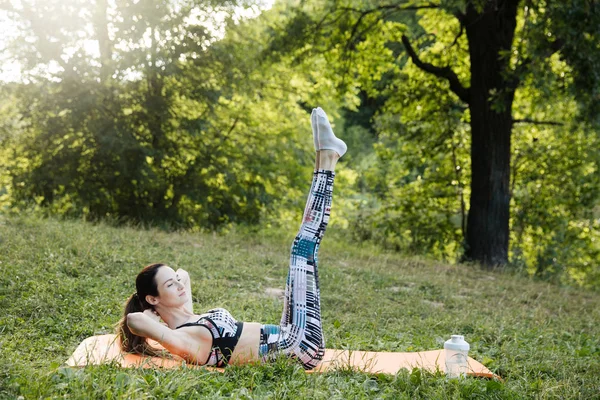 The girl is engaged in fitness and meditates in the park city — Stock Photo, Image