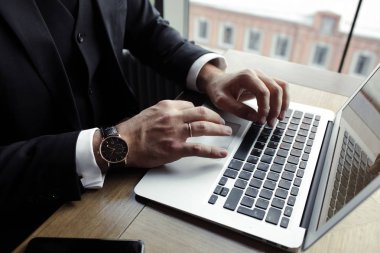 eller erkekler dizüstü bilgisayarda, bir telefon ve kapuçino yakınında yalan