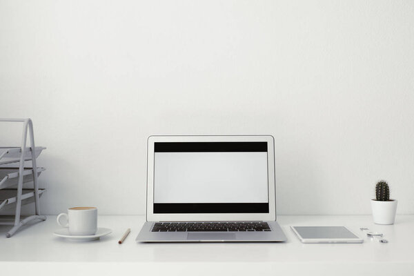 office table on which laptop, coffee, tablet, camera and other items