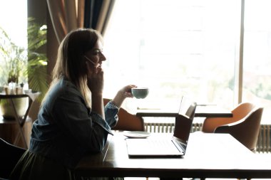 Genç kız kahve içme ve telefonda konuşmak