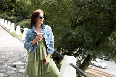 Genç kız sokakta kahve içme ve yürüyüş