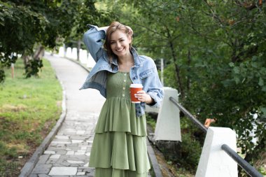 Genç kız sokakta kahve içme ve yürüyüş