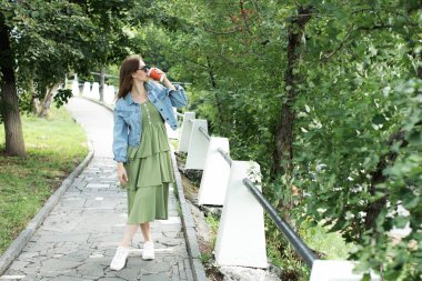 Genç kız sokakta kahve içme ve yürüyüş