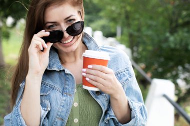 Genç kız sokakta kahve içme ve yürüyüş