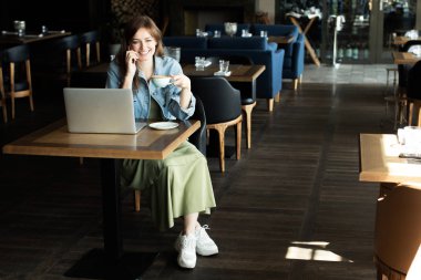 Genç kız kahve içme ve telefonda konuşmak