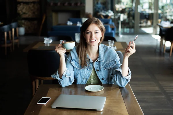 Молодая девушка улыбается и пьет кофе — стоковое фото