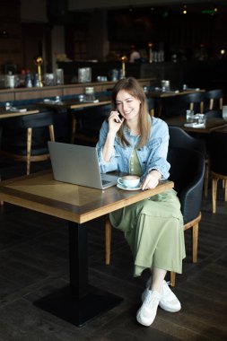 Genç kız kahve içme ve telefonda konuşmak