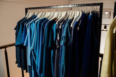 Butikte askılarda asılı çeşitli şık kıyafetlerin yakın plan görüntüsü. Giysiler