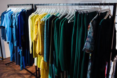 Butikte askılarda asılı çeşitli şık kıyafetlerin yakın plan görüntüsü. Giysiler