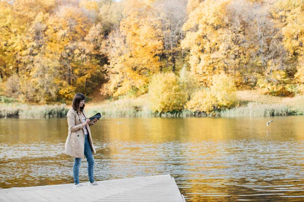 Молодая девушка рисует около озера в осеннем лесу . — стоковое фото