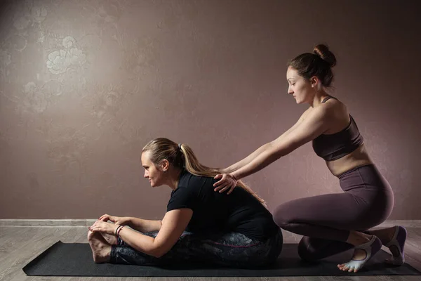 Dos jóvenes deportistas practicando yoga, meditando en la pose Half Lotus, haciendo ejercicio, usando ropa deportiva, estudio de yoga marrón — Foto de Stock