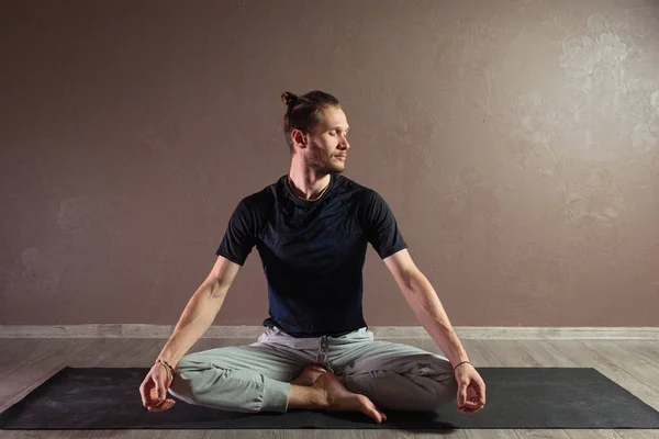 Joven deportista practicando yoga, meditando en la pose Half Lotus, haciendo ejercicio, usando ropa deportiva, estudio de yoga gris — Foto de Stock