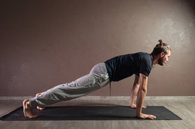 Genç sporcu yoga yapıyor, yarım Lotus pozisyonunda meditasyon yapıyor spor kıyafetleri giyiyor, kapalı alanda yoga yapıyor, kahverengi yoga stüdyosu.