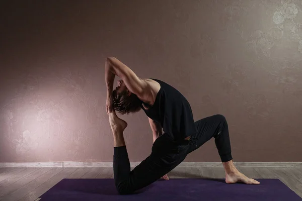 Joven deportista practicando yoga, meditando en pose de yoga, haciendo ejercicio, usando ropa deportiva, estudio de yoga marrón — Foto de Stock