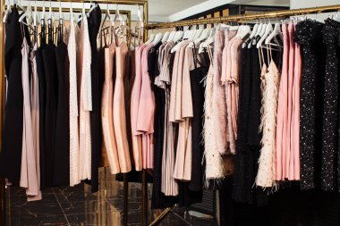 Butikte askılarda asılı çeşitli şık kıyafetlerin yakın plan görüntüsü. Giysiler