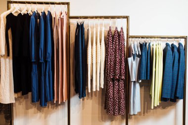 Butikte askılarda asılı çeşitli şık kıyafetlerin yakın plan görüntüsü. Giysiler