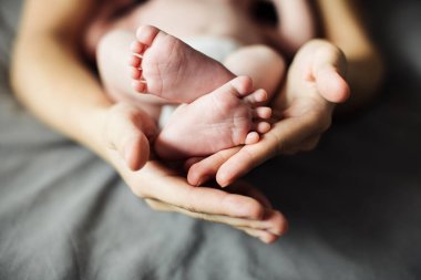 Anne yeni doğmuş bebek ayaklarını elinde tutuyor. Annem banyo yaptıktan sonra bebeğe bakıyor. Ebeveynler çocuk bakıcılığı. Çocuk sağlığı ve mutlu bir aile.