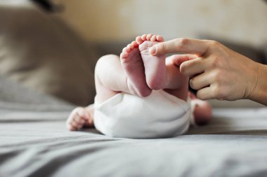 Anne yeni doğmuş bebek ayaklarını elinde tutuyor. Annem banyo yaptıktan sonra bebeğe bakıyor. Ebeveynler çocuk bakıcılığı. Çocuk sağlığı ve mutlu bir aile.