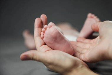 Anne yeni doğmuş bebek ayaklarını elinde tutuyor. Annem banyo yaptıktan sonra bebeğe bakıyor. Ebeveynler çocuk bakıcılığı. Çocuk sağlığı ve mutlu bir aile.