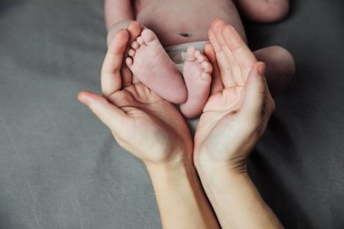 Anne yeni doğmuş bebek ayaklarını elinde tutuyor. Annem banyo yaptıktan sonra bebeğe bakıyor. Ebeveynler çocuk bakıcılığı. Çocuk sağlığı ve mutlu bir aile.