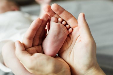 Anne yeni doğmuş bebek ayaklarını elinde tutuyor. Annem banyo yaptıktan sonra bebeğe bakıyor. Ebeveynler çocuk bakıcılığı. Çocuk sağlığı ve mutlu bir aile.