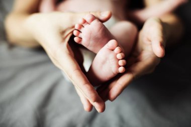 Anne yeni doğmuş bebek ayaklarını elinde tutuyor. Annem banyo yaptıktan sonra bebeğe bakıyor. Ebeveynler çocuk bakıcılığı. Çocuk sağlığı ve mutlu bir aile.