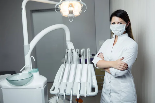 Portrait of female dentist .She standing in her dentist office. Female dentist wearing a white robe