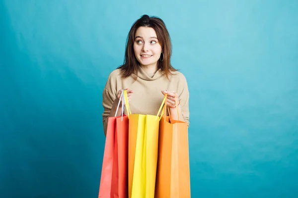 파란 배경에서 쇼핑백을 들고 있는 행복 한 소녀의 모습 — 스톡 사진